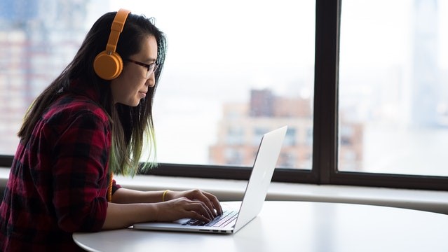 female student working on laptop and wearing headphones