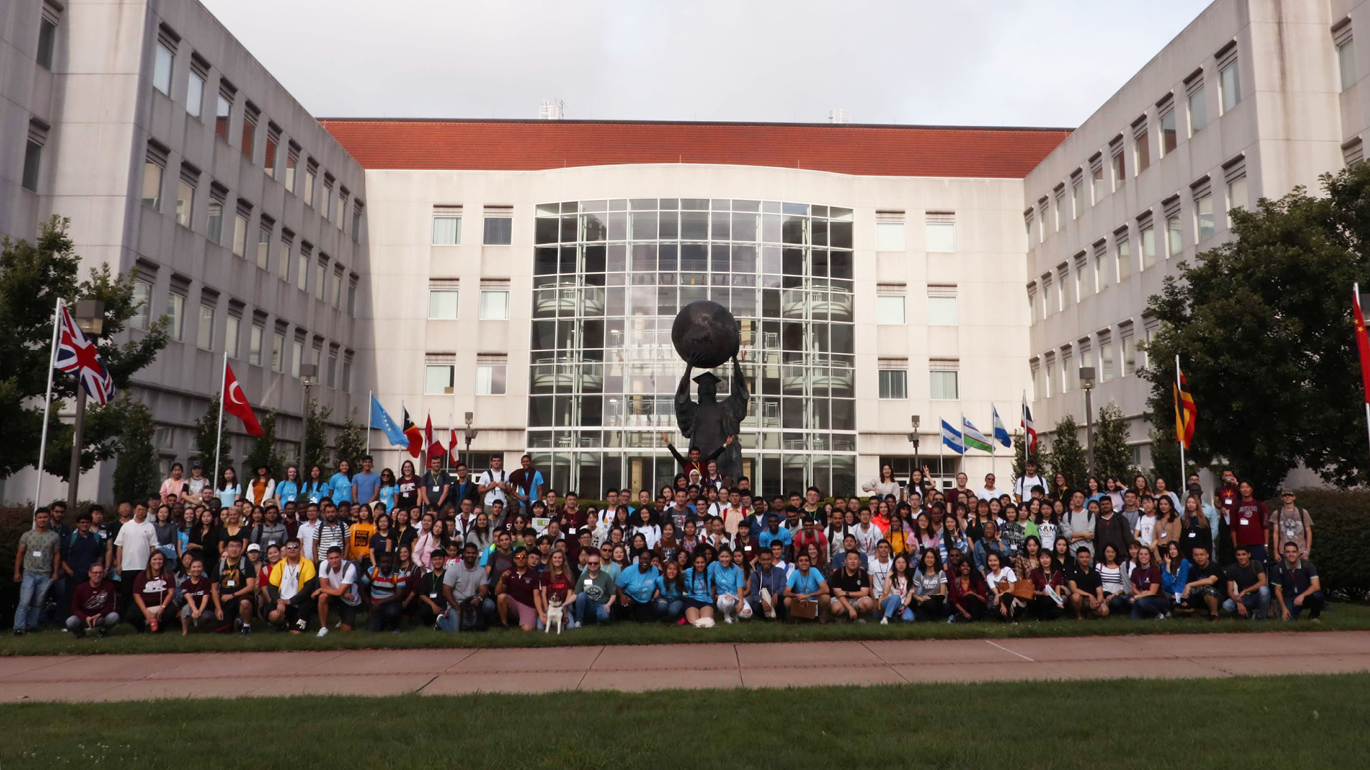 Over 200 new international students pose with the Citizen Scholar statue on campus at Missouri State during orientation.