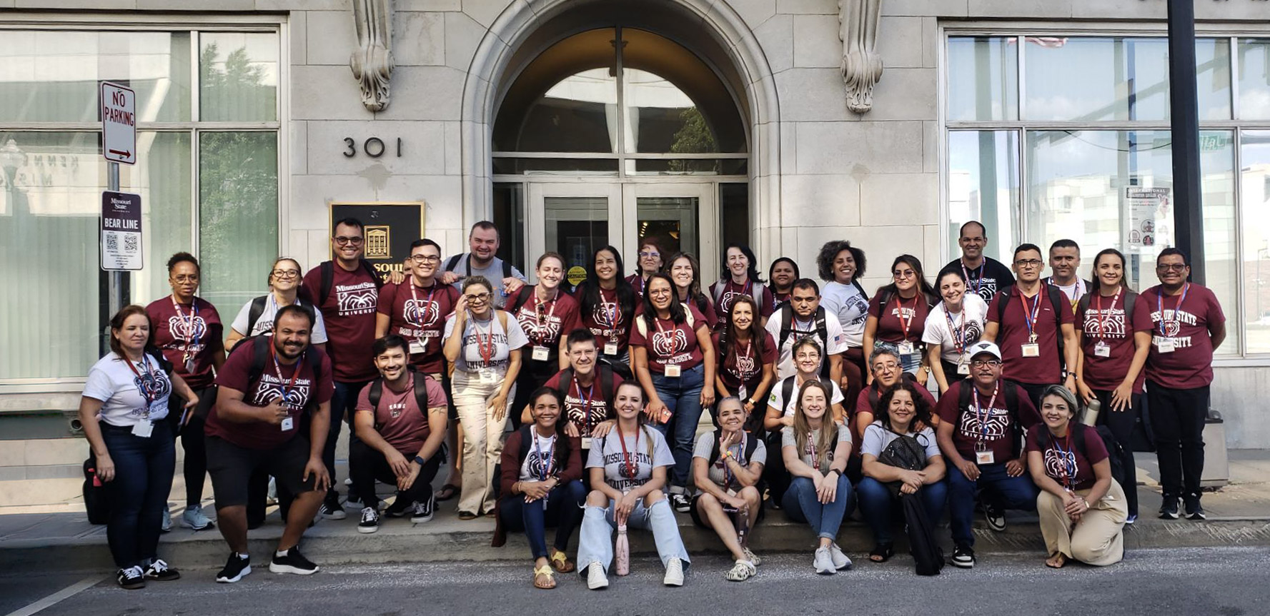 A large group in Missouri State University shirts poses for a photo in front of a building.